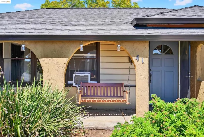 Doorway to property with a shingled roof, covered porch, and stucco siding