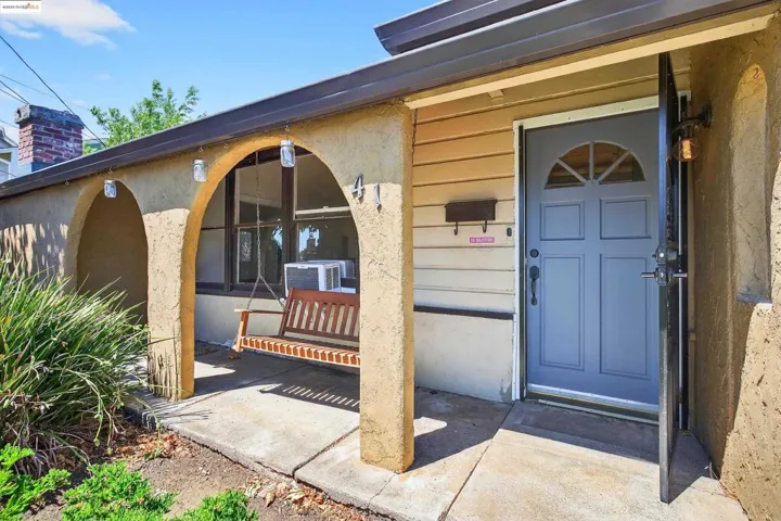 Doorway to property featuring a porch, cooling unit, stucco siding, and a chimney