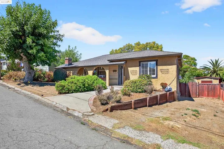 Single story home featuring stucco siding, roof with shingles, and a chimney