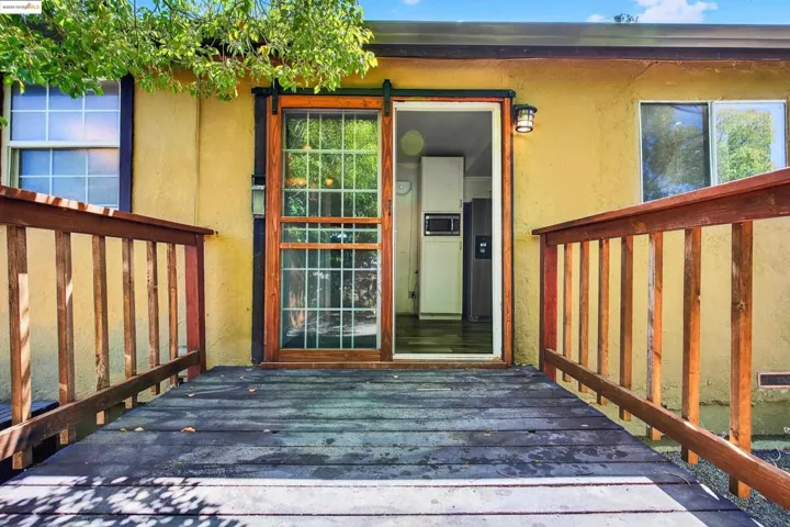 View of exterior entry with stucco siding and a wooden deck