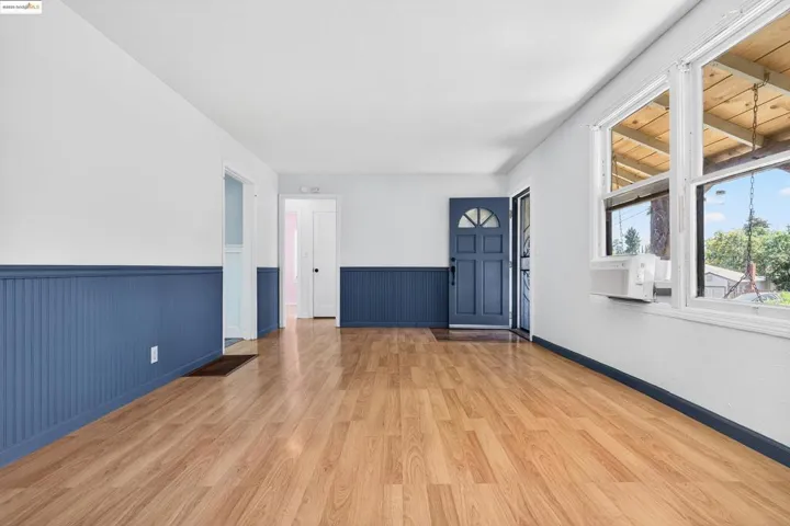 Unfurnished living room featuring a wainscoted wall and light wood-style floors