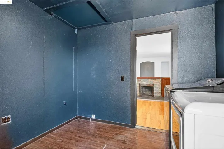 Laundry room with washer and dryer, a textured wall, wood finished floors, and a fireplace with raised hearth