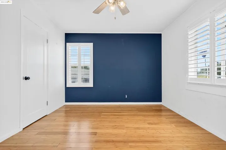 Spare room featuring wood finished floors, ceiling fan, and crown molding