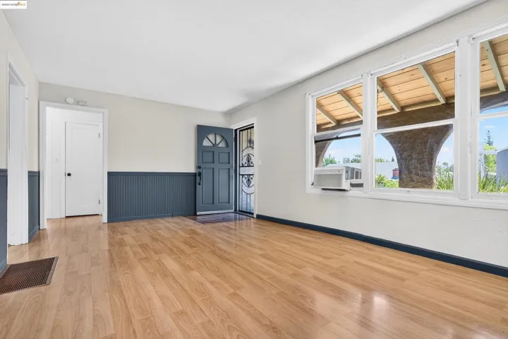 Entryway featuring light wood-style flooring, a wainscoted wall, and cooling unit