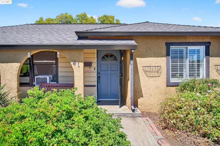 Property entrance featuring a shingled roof, stucco siding, and covered porch