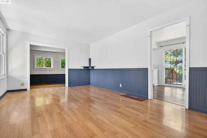 Empty room with wainscoting, healthy amount of natural light, and wood finished floors