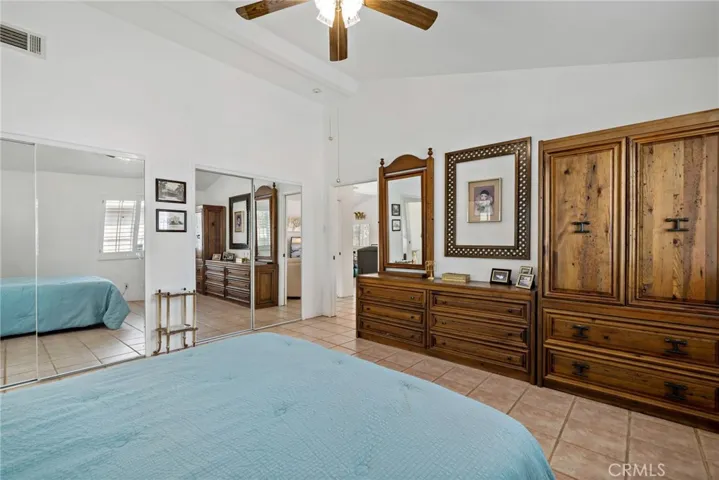 Reverse angle of primary bedroom w two closets w mirrored sliding doors.