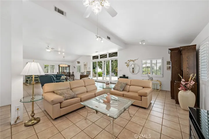 Main living area w tile flooring, ceiling fan/light fixtures and double sliding french door entry