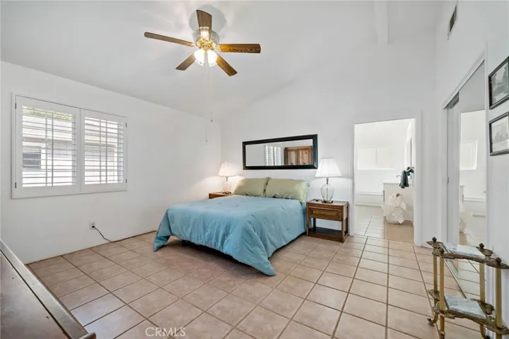 Primary bedroom w ceiling fan/light fixture, window shutters and doorway to bathroom at right.