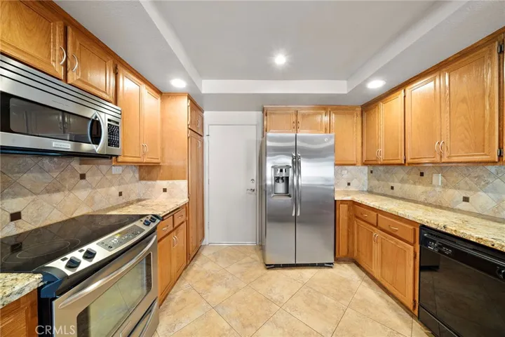 The Upgraded Kitchen Features Granite Countertops, a Breakfast Bar, Recessed Lighting, an Abundance of Cabinetry, Tile Flooring, Electric Range, Dishwasher, and Built-In Microwave.