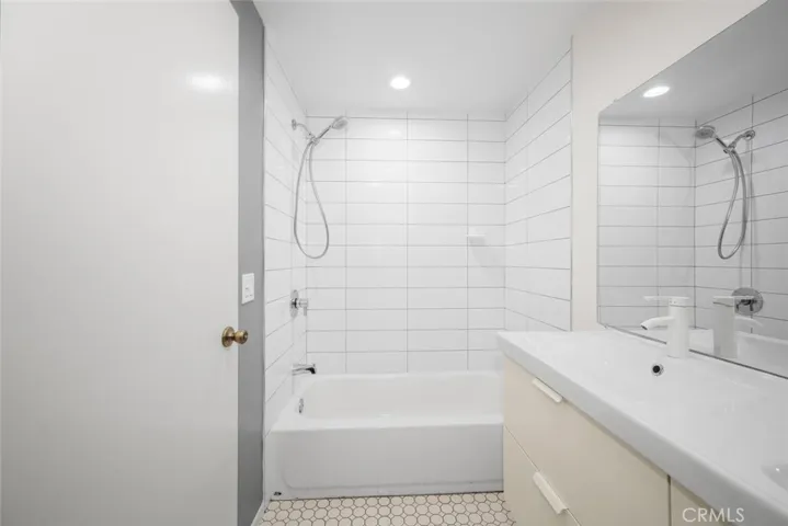Upstairs remodeled bathroom with integrated ceramic dual sink wash basin and nicely tiled shower walls. This bathroom also features High Gloss European style vanity and tasteful flooring.