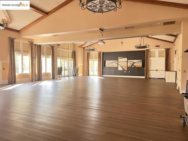 Misc room with dark wood-style floors, beamed ceiling, high vaulted ceiling, a chandelier, and plenty of natural light