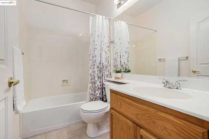 Full bathroom featuring shower / bath combination with curtain, light tile patterned flooring, and vanity
