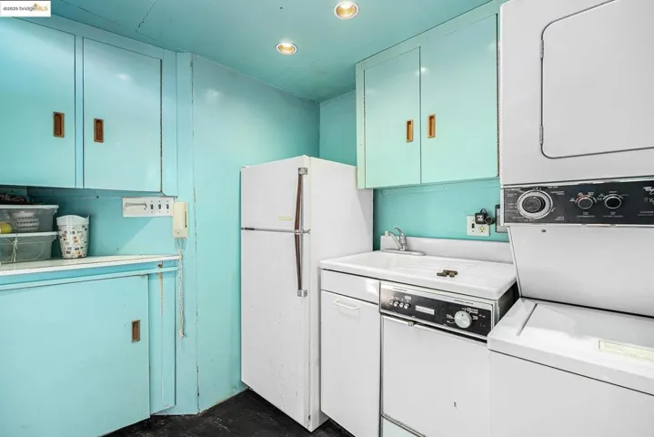 Kitchen featuring stacked washer / dryer, light countertops, freestanding refrigerator, and recessed lighting