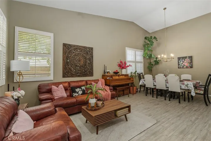Full view of the home’s entry, featuring the living and dining areas with tiled flooring, vaulted ceilings, and shutters.