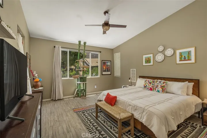 Primary suite features a vaulted ceiling, ceiling fan, and tiled floors.