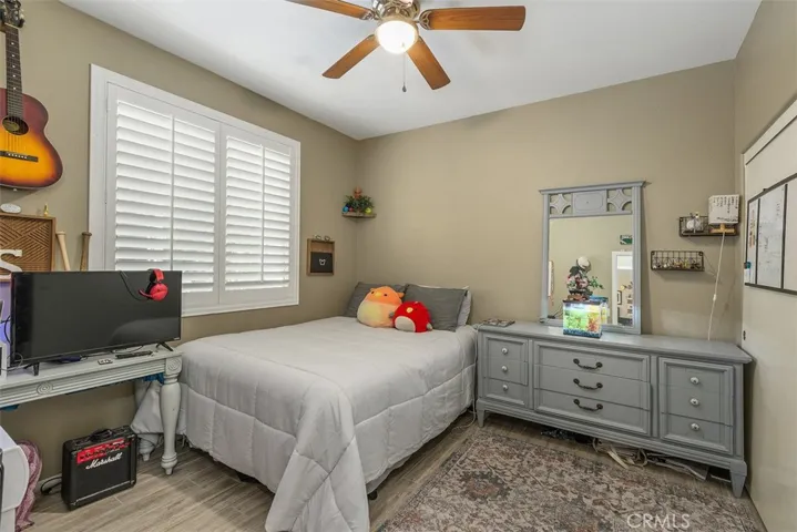 Bedroom 3 with ceiling fan, tiled floors, and shutters.