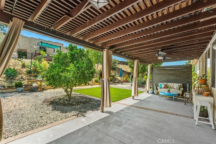 Covered backyard patio with ceiling fan.