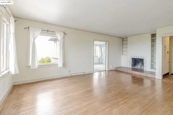 Unfurnished living room with built in shelves, light wood-type flooring, and a tiled fireplace