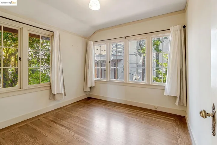 Unfurnished room with wood finished floors and vaulted ceiling