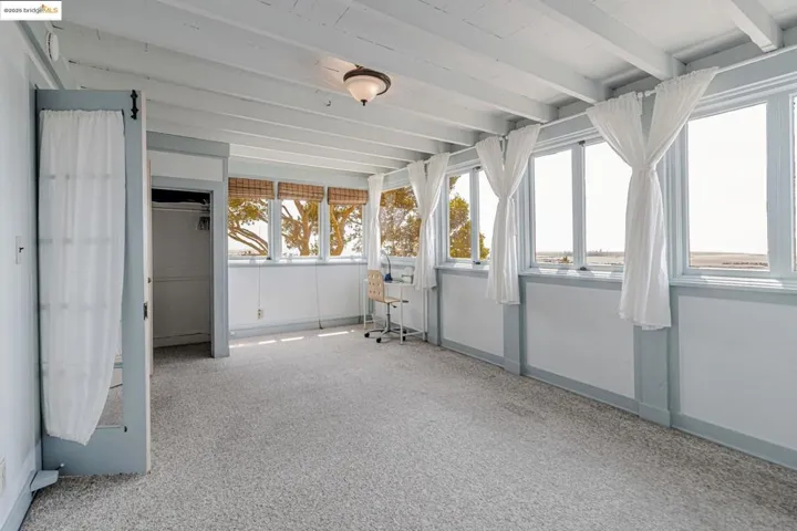 Unfurnished sunroom with beam ceiling and carpet