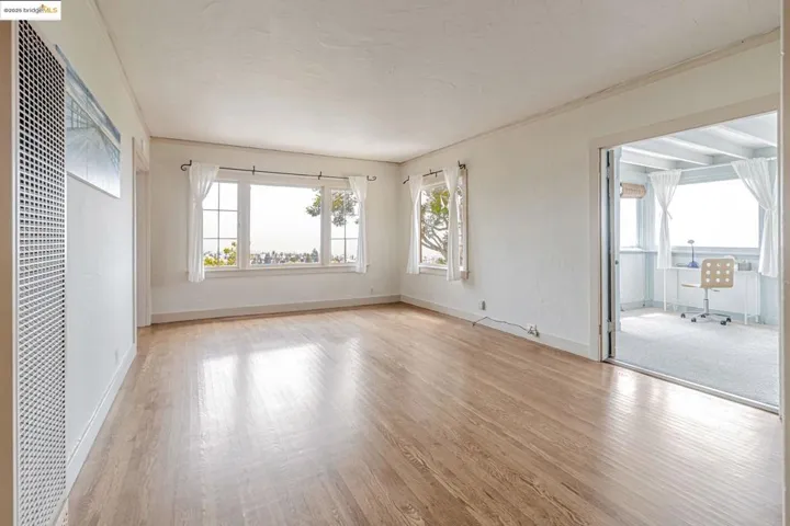 Empty room featuring a heating unit, ornamental molding, and light wood-style floors