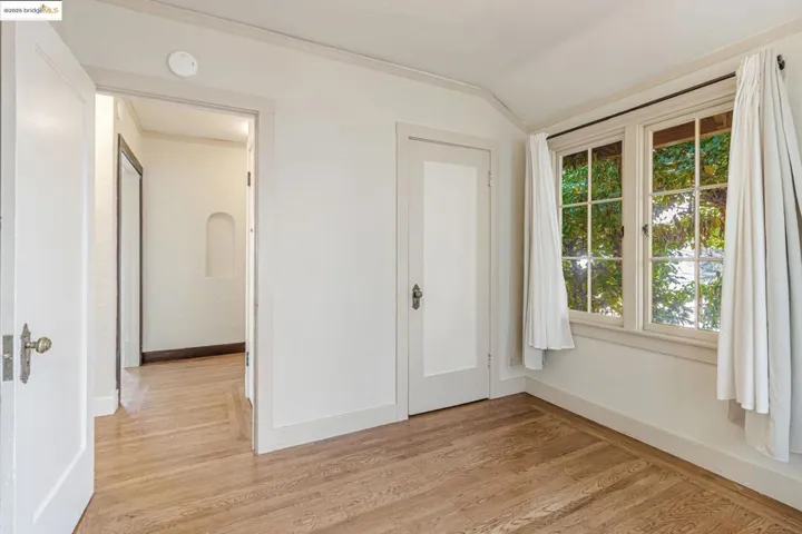 Unfurnished room with light wood finished floors, vaulted ceiling, and ornamental molding