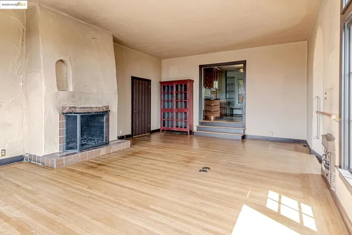 Unfurnished living room with a tiled fireplace and light wood-style floors
