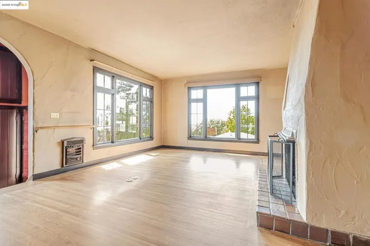 Unfurnished living room featuring a textured wall, a fireplace, heating unit, wood finished floors, and arched walkways