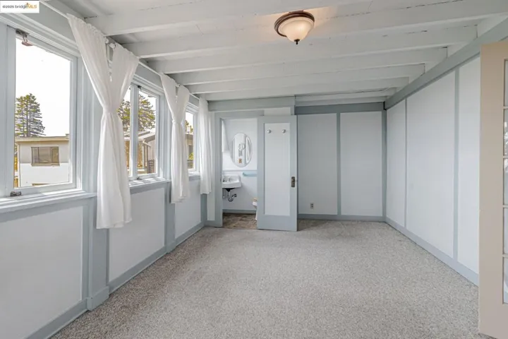Unfurnished sunroom with carpet flooring and beam ceiling