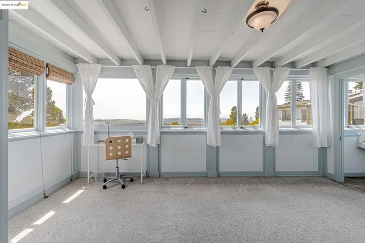 Unfurnished sunroom featuring beam ceiling and carpet