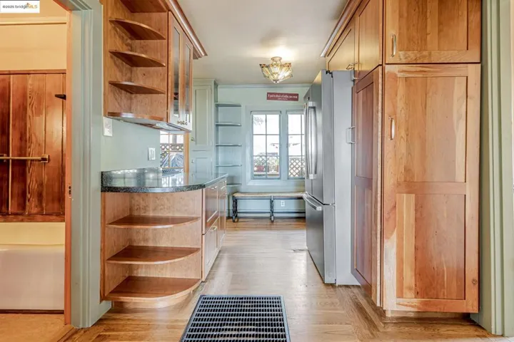 Kitchen with open shelves, freestanding refrigerator, dark countertops, and light wood finished floors