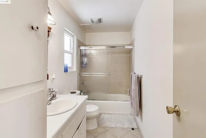 Bathroom with vanity, combined bath / shower with glass door, and light tile patterned flooring
