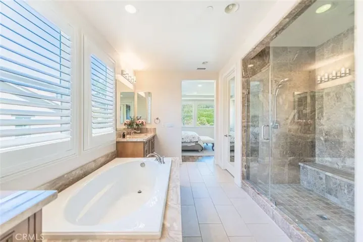 The primary bathroom offers a spa-like retreat with double vanity, a luxurious drop-in soaking tub, and a large walk-in shower, combining style and functionality.
