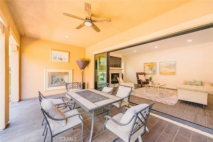 The covered backyard patio, complete with a fireplace, flows effortlessly into the living room, blending indoor and outdoor living for year-round comfort and entertaining.