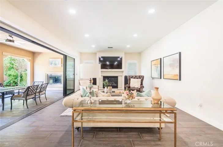 The living room features large sliding windows that open fully to the outside patio, seamlessly blending indoor and outdoor living and allowing fresh air to flow freely throughout the space.