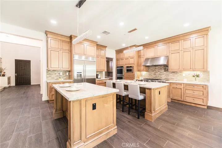 The chef’s kitchen boasts two oversized islands for both prep and seating, complemented by a built-in refrigerator, double ovens, and high-end finishes.