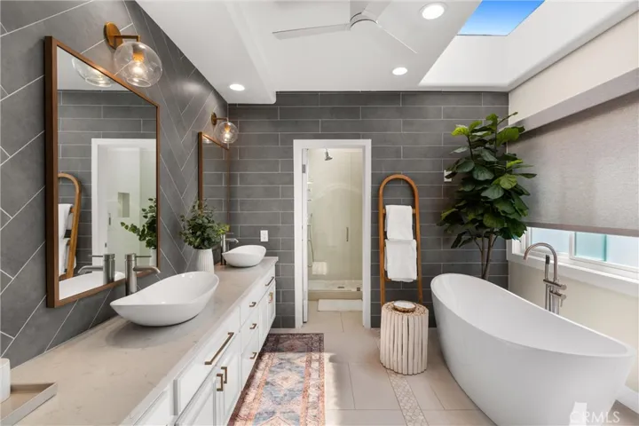 Spa-inspired bathroom includes dual vessel sinks, sleek quartz countertops, and striking herringbone tile accents.