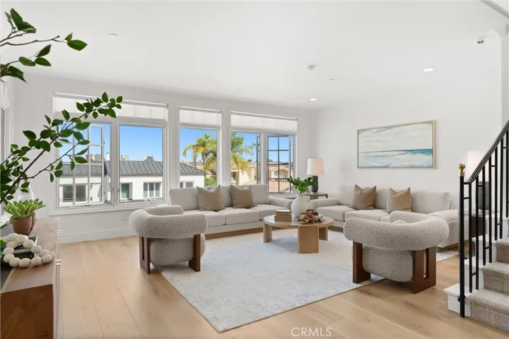 Sun-filled living room showcases a wall of custom windows for ocean breezes and  serene neighborhood and ocean views.