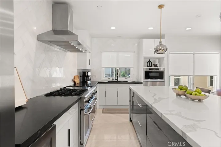 The gourmet kitchen showcases an oversized waterfall island, sleek cabinetry, and top-tier stainless steel a Entertain with ease at the expansive island featuring stylish pendant lighting and seating for four appliances.