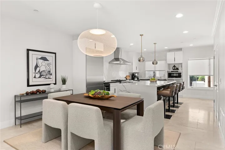 Sleek dining space flows into the chef’s kitchen with stone countertops, oversized island, and high-end appliances.
