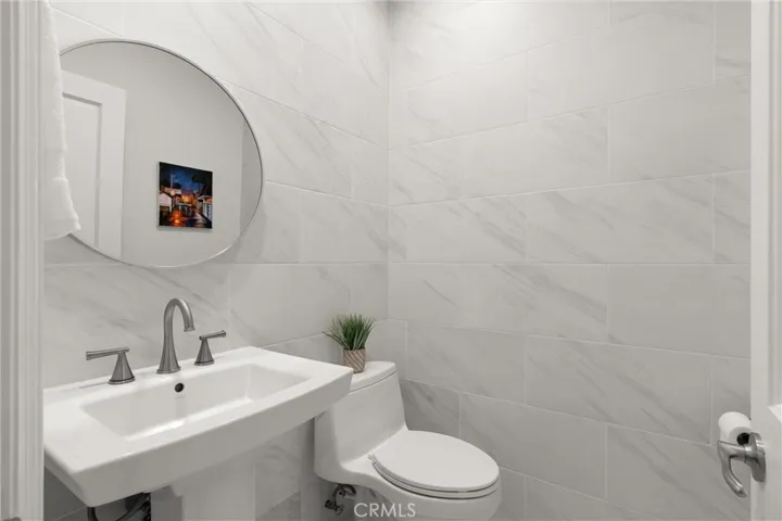Modern powder room with marble tile and pedestal sink.