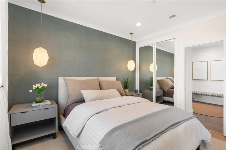 Elegant guest room with mirrored closet doors and designer pendant lighting.
