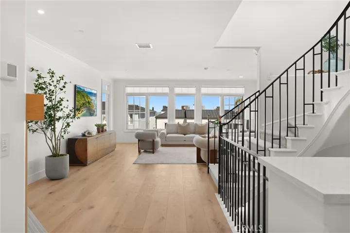 Light-filled living space with wide-plank wood floors and expansive windows invites ocean breezes and natural light.