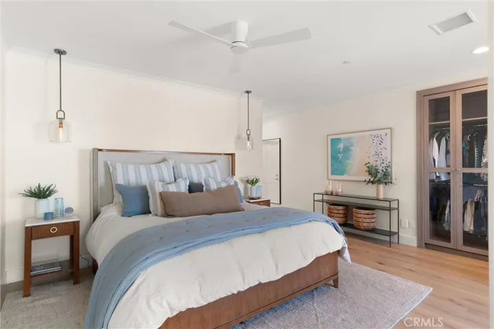 The serene primary bedroom features designer lighting, an ultra-quiet ceiling fan, and custom built-in wardrobes with glass doors.