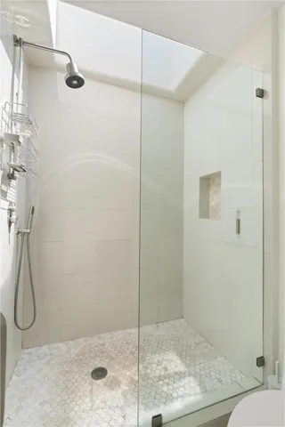 Glass-enclosed walk-in shower with built-in niche and skylight combines style with modern convenience