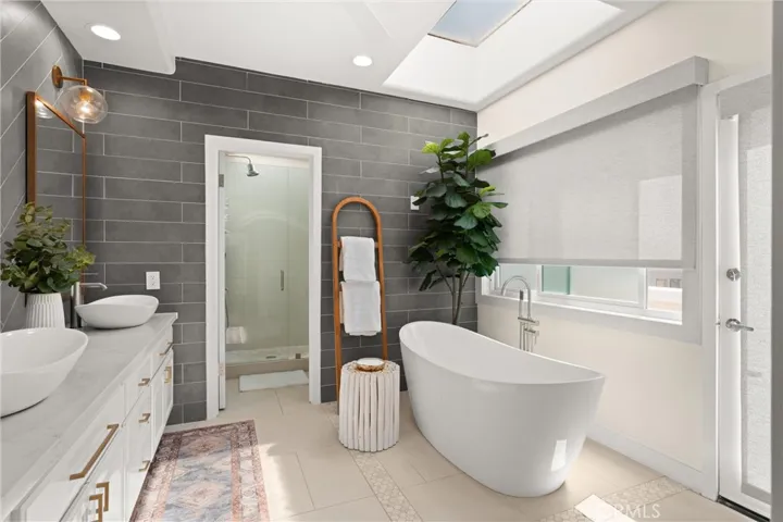 A freestanding soaking tub is perfectly situated beside shaded windows for light and privacy.