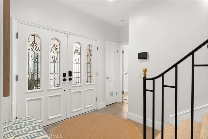 Welcoming entryway with decorative glass double doors and an elegant staircase
