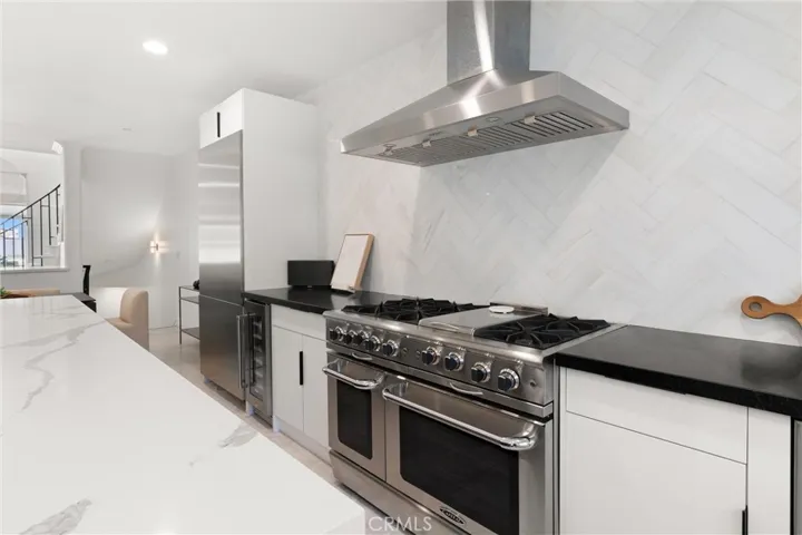 Professional-grade appliances include a 6-burner range with cooktop and double oven, oversized refrigerator, and wine fridge.