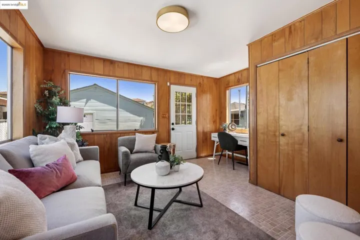 Living room with wooden walls, brick patterned floors, and a desk